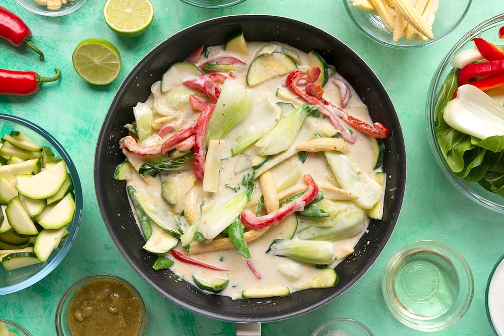 a black wok filled with bok choi, sweetcorn, red pepper, bamboo, sugar snap peas and courgette cooked in a yogurt curry sauce.