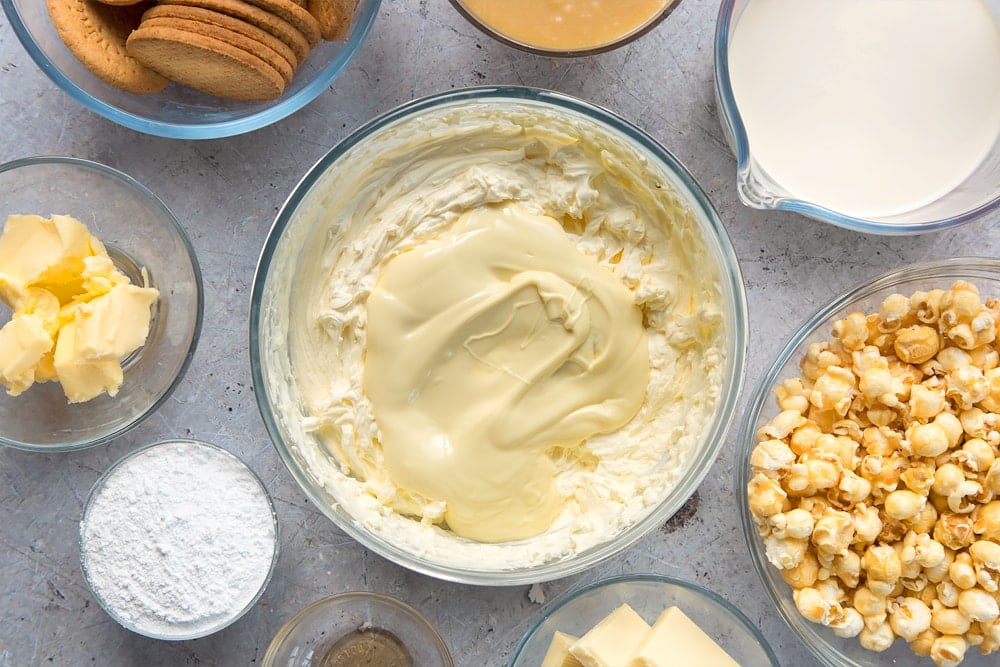 whisked cream cheese, cream, sugar and vanilla in clear bowl topped with melted white chocolate