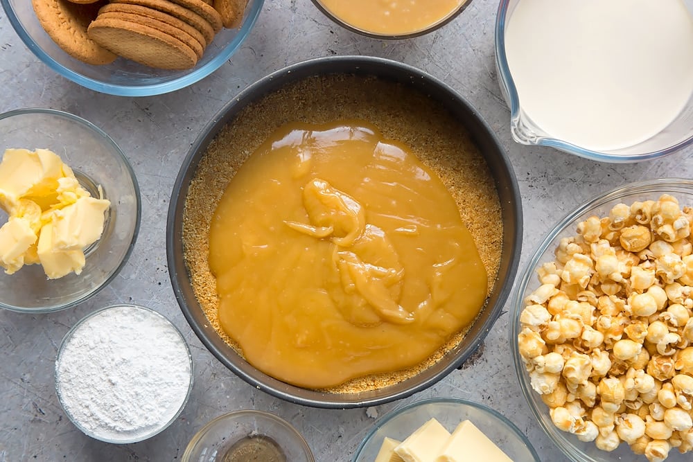 over head view of the biscuit base topped with smooth caramel in a cake tin.