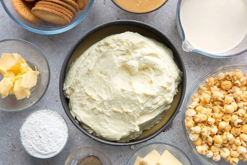 frozen cheesecake base topped with caramel and whipped cheesecake mixture in a cake tin.