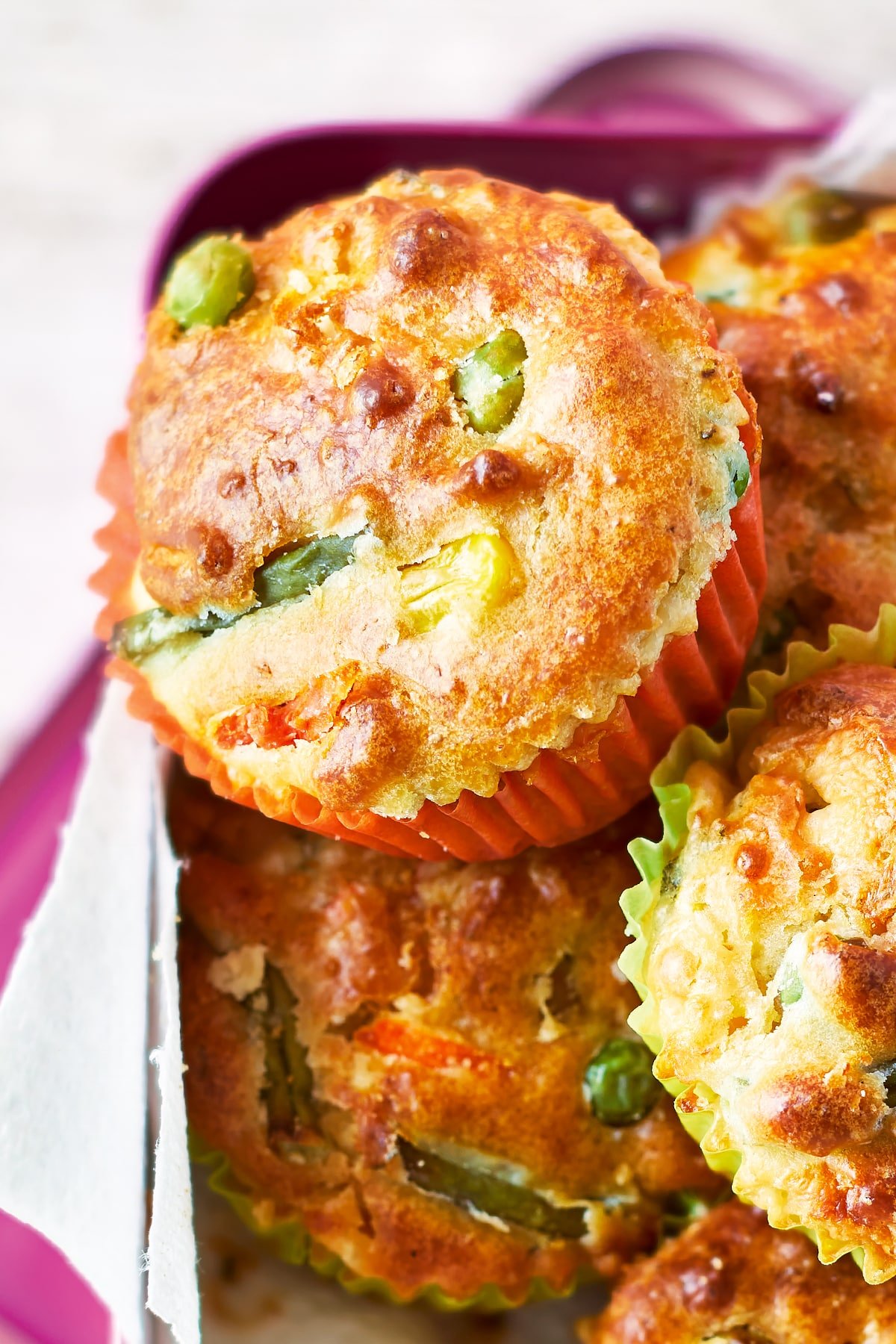 Savoury vegetable muffins in a pink lunchbox lined with paper.