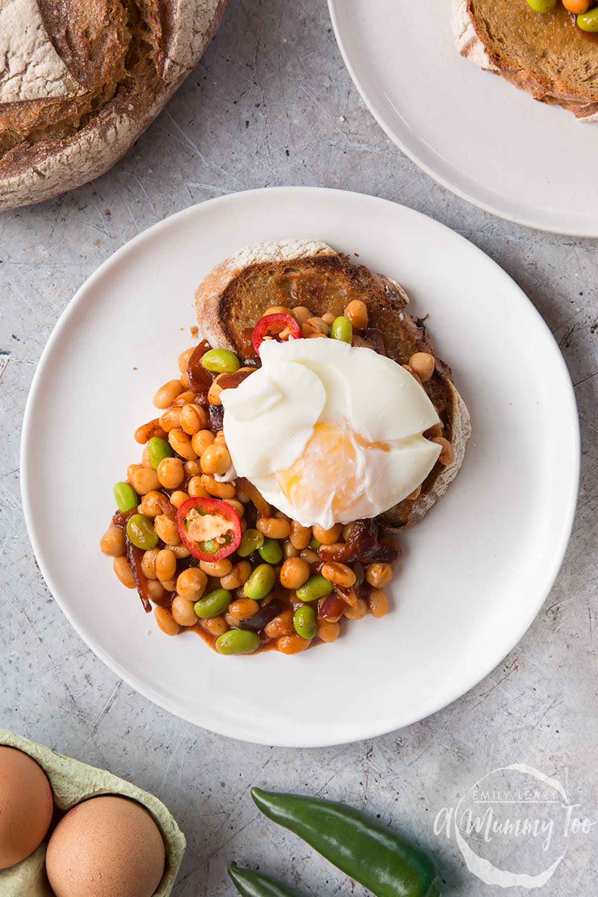 Breakfast beans with chilli, chickpeas and edamame served on sour dough toast with a poached egg on top. The yolk is not yet broken. 