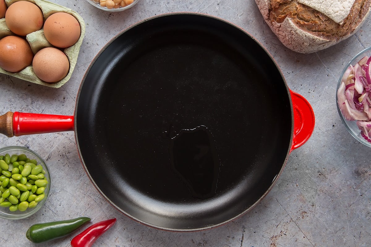 A pan with a little oil, surrounded by ingredients to make breakfast beans.