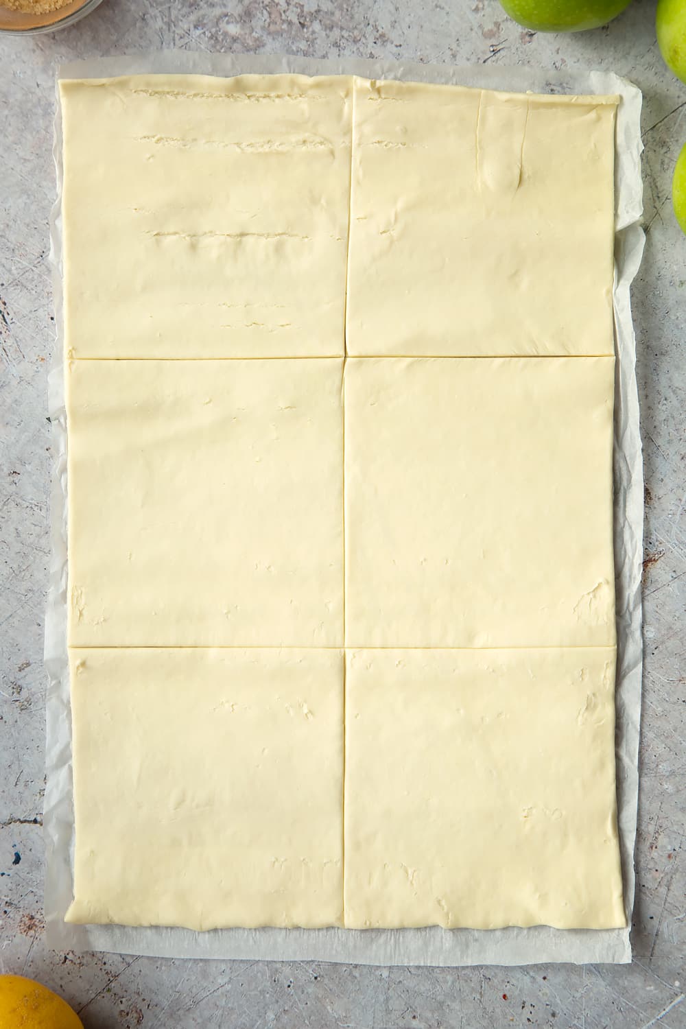 Overhead shot of one sheet of puff pastry with six divisions laid on a speckled surface