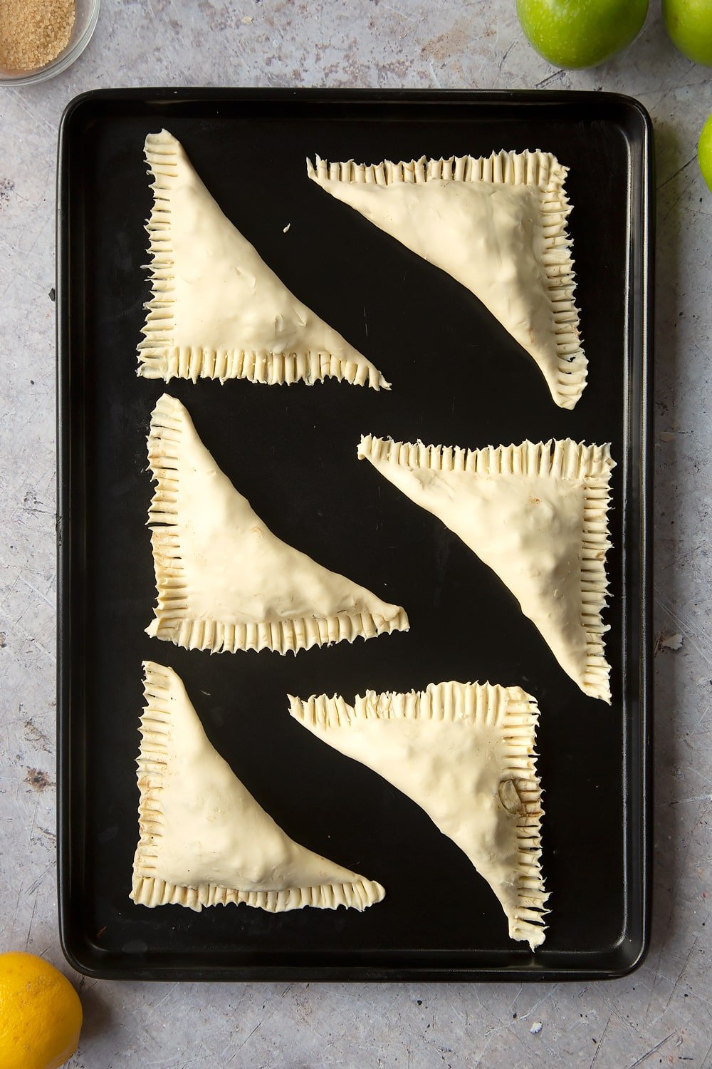 Overhead shot of the finished apple turnovers on a baking tray before going into the oven.