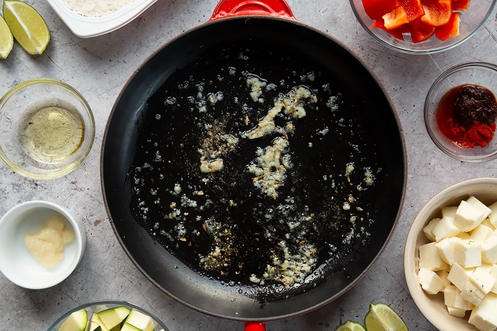 Overhead shot of oil, garlic, and fennel seeds in a large pan 