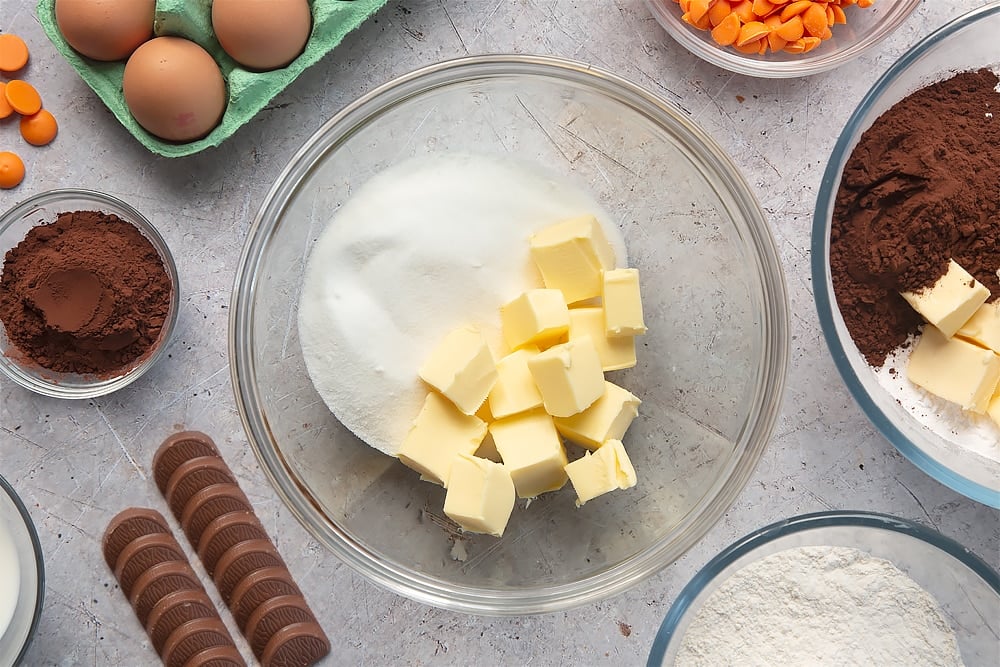 Overhead shot of butter and sugar in a large clear mixing bowl