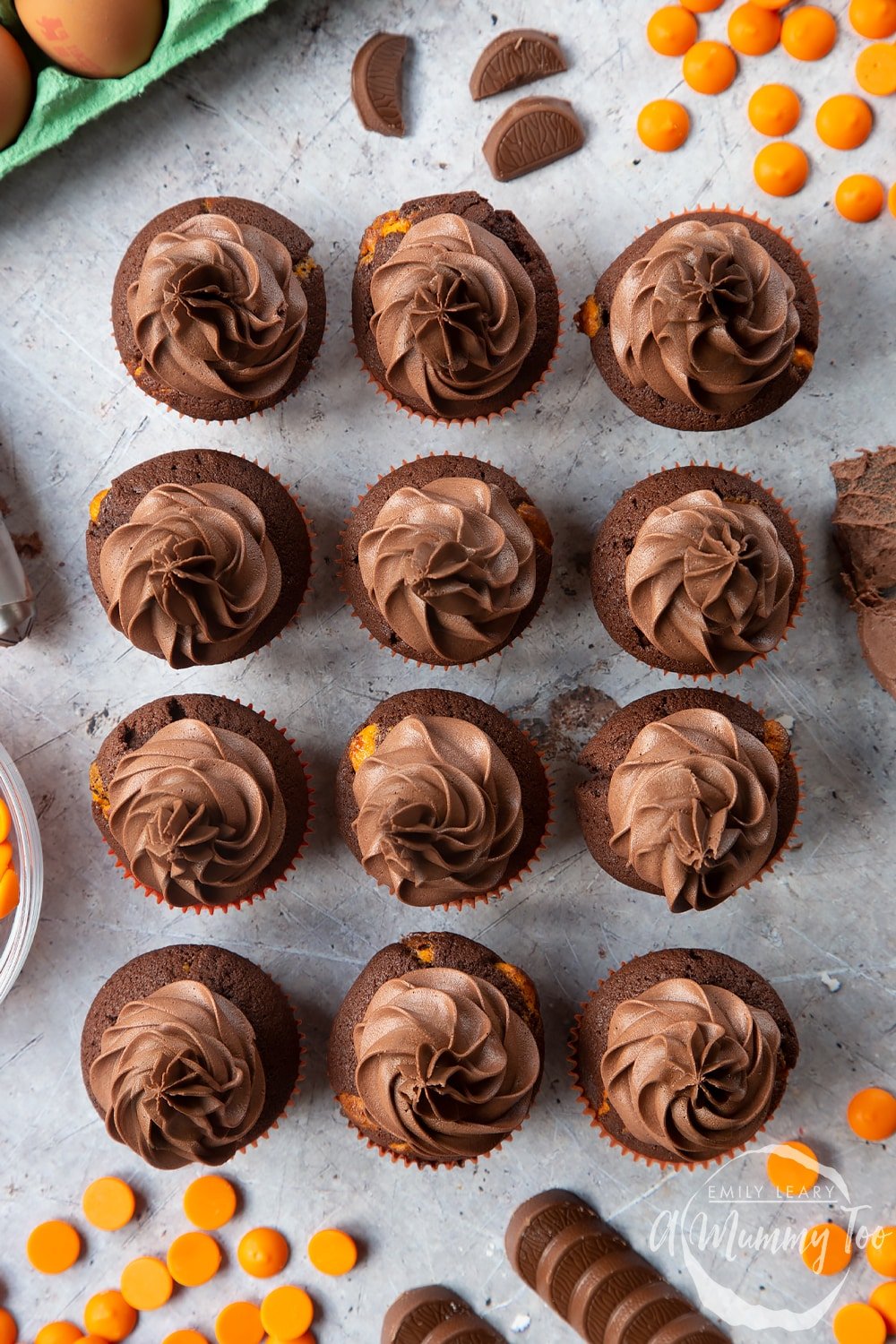 Overhead shot of chocolate orange muffins with a mummy too logo in the lower-right corner
