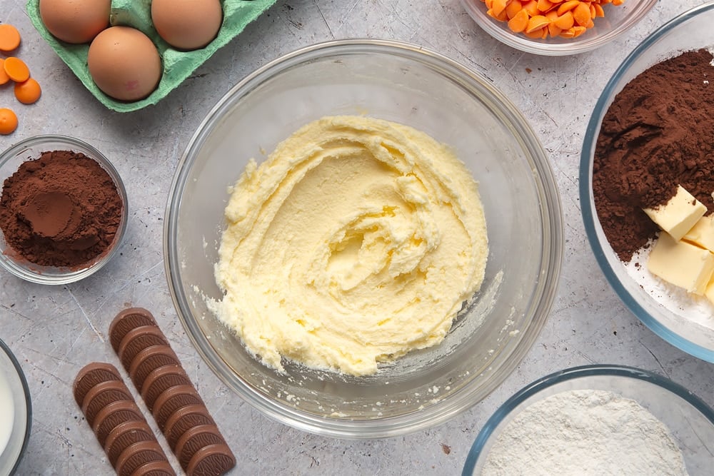 Overhead shot of butter and sugar mixture in a large clear mixing bowl