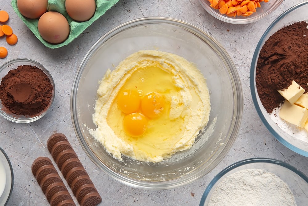 Overhead shot of butter mixture with three eggs in a large mixing bowl