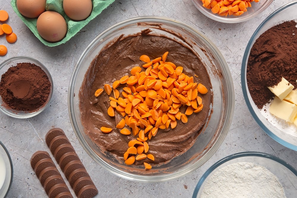 Overhead shot of chocolate muffin batter topped with chocolate orange buttons in a large mixing bowl