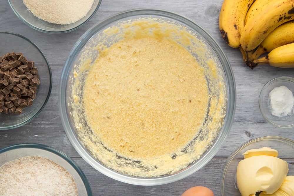Overhead shot of mashed banana flour and baking powder in a large bowl