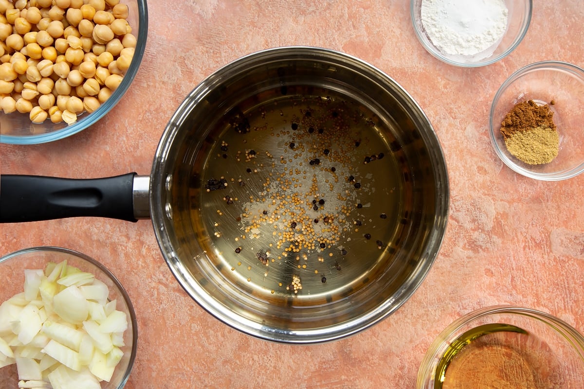 A saucepan containing pickling liquor made from salt, mustard seeds and peppercorns.