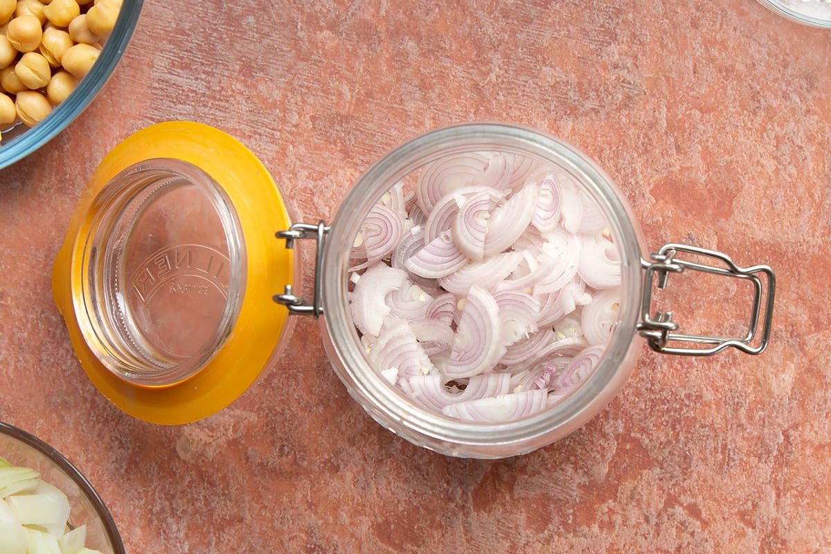 A preserving jar containing thinly sliced shallots.