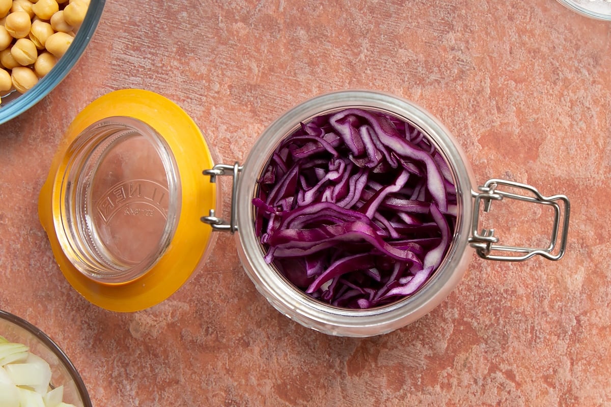 A preserving jar containing thinly sliced shallots and red cabbage.