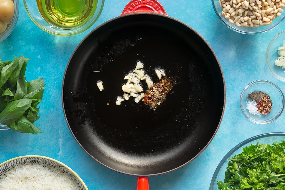 A pan containing olive oil, garlic, chilli salt and pepper. The pan is surrounded by ingredients for kale pesto linguine.