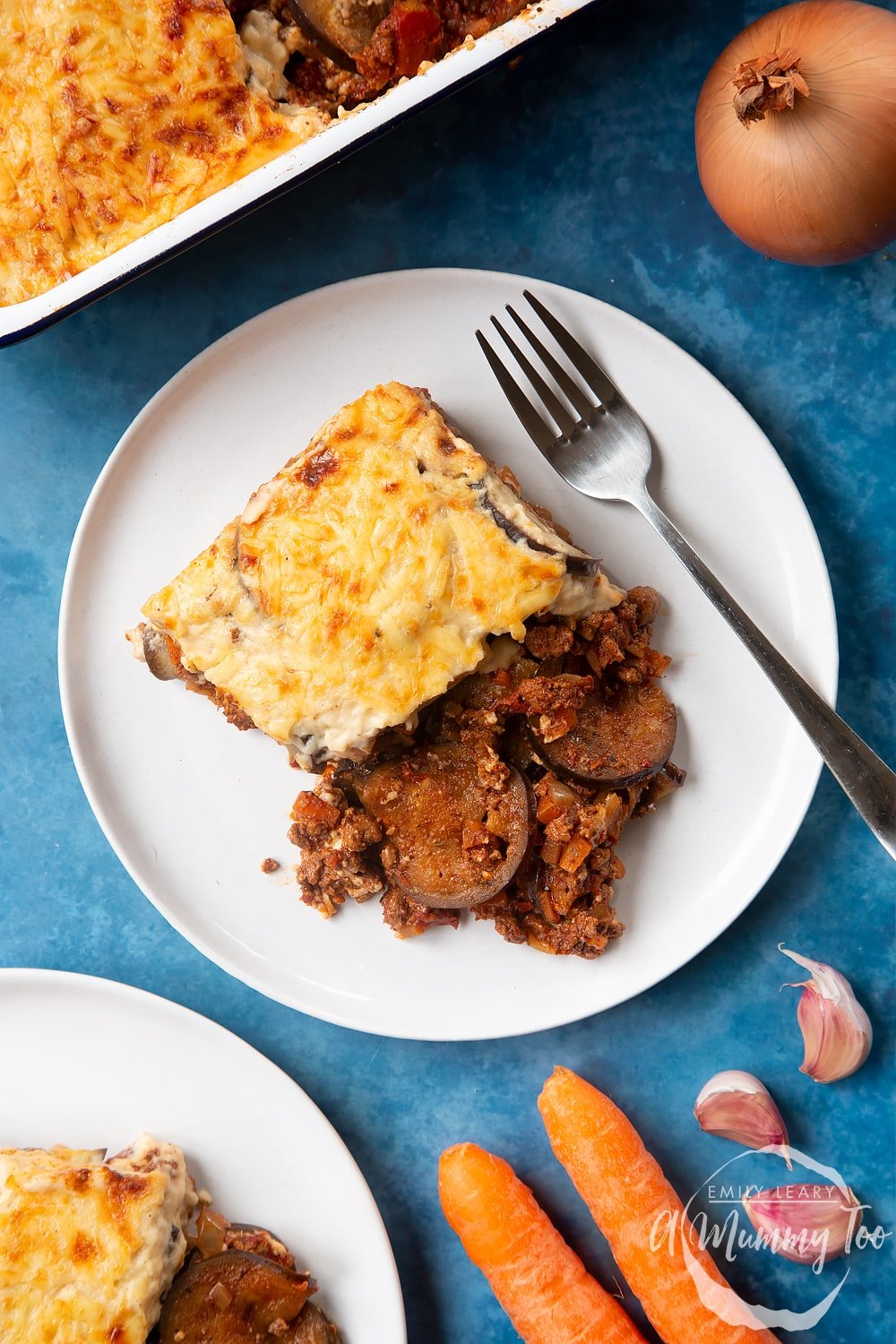 Overhead shot of Quorn Meat Free Mince Moussaka with fork on the side served on a white plate with brand logo in the lower-right corner