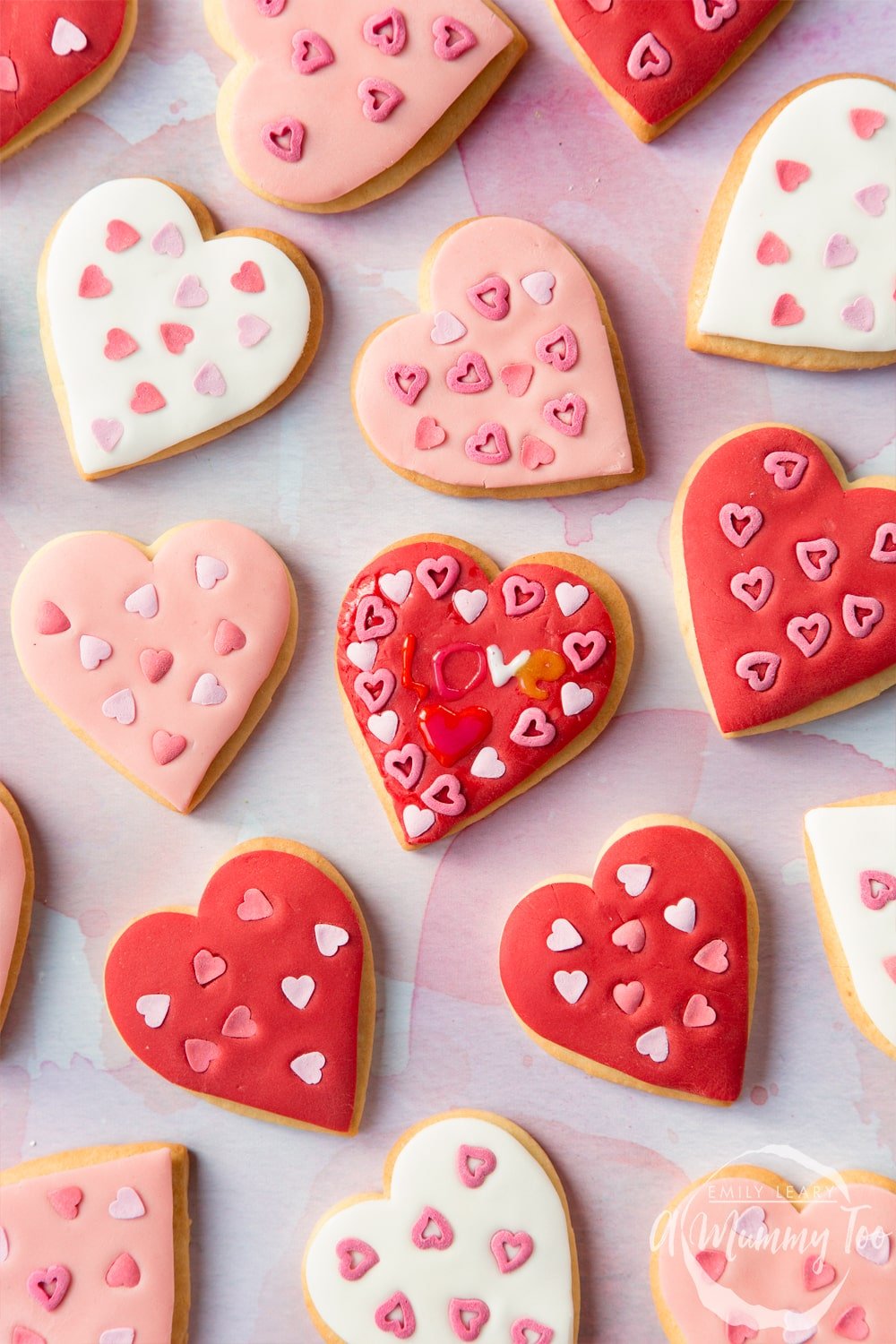 Overhead shot of Valentines day cookies with additional icing writing with the A Mummy Too logo in the bottom right hand corner