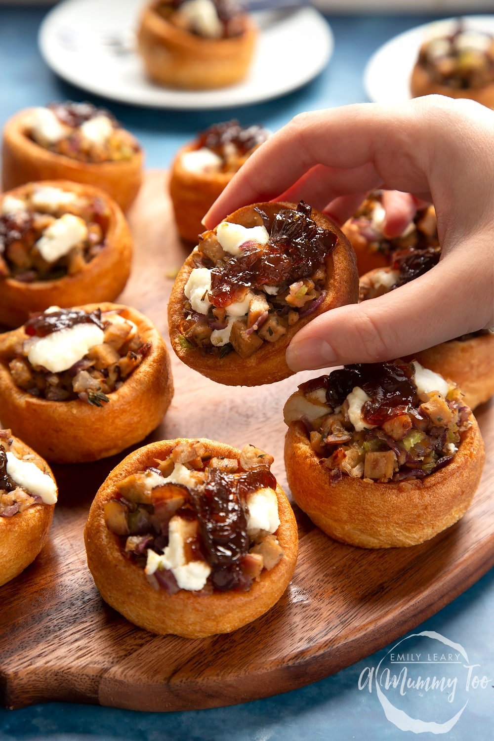 a hand holding a mini yorkshire pudding stuffed with vegetables and cheese.