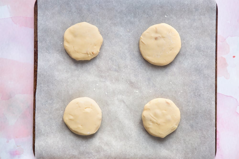 Overhead shot of four cookie dough balls in a paper-lined baking sheet