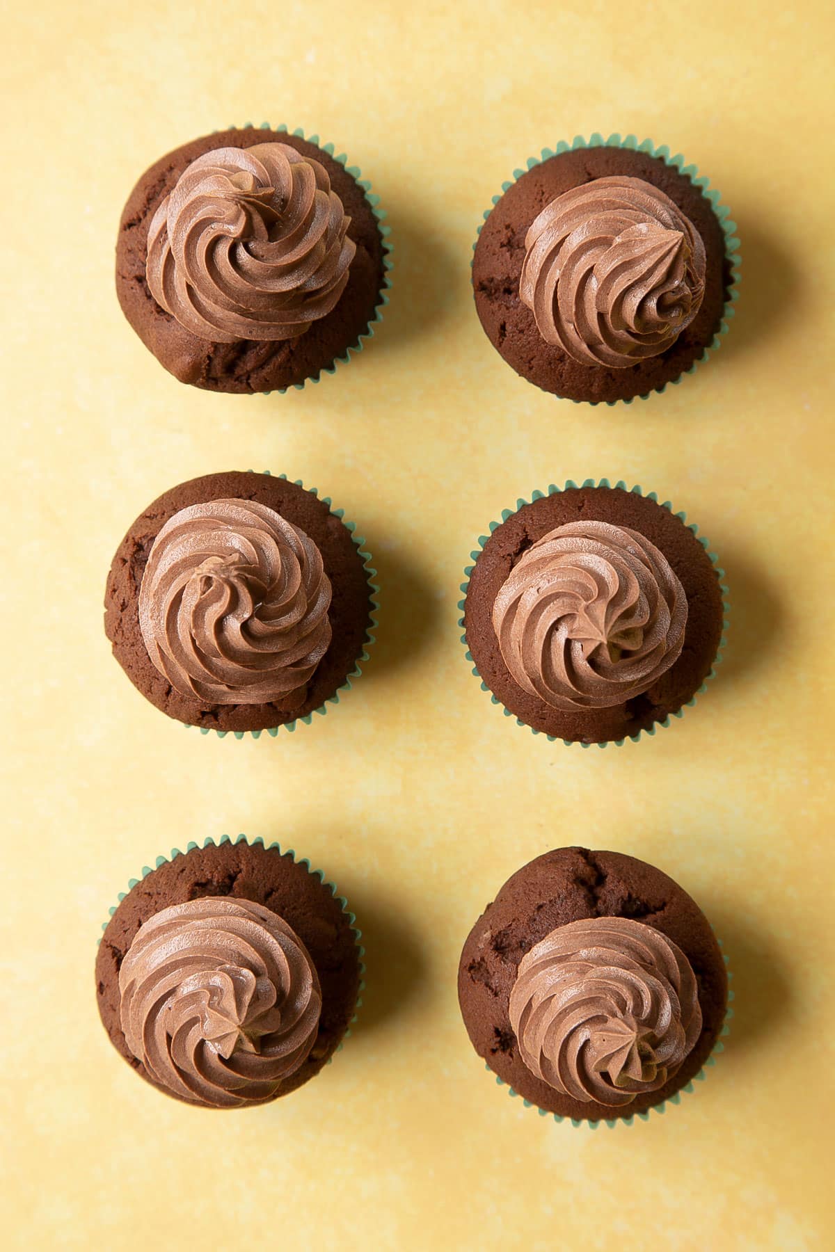 Chocolate walnut cupcakes with chocolate frosting piped on top in tall swirls.