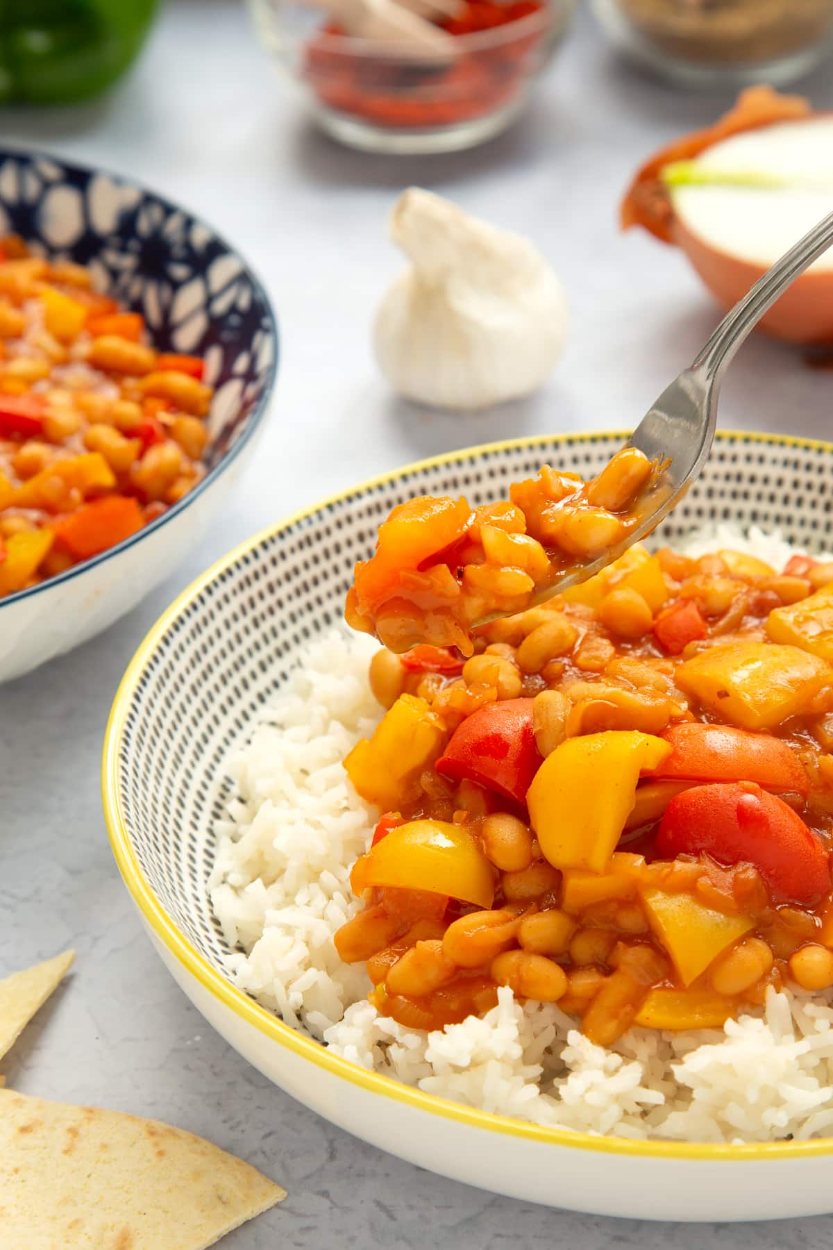 Baked bean chilli served on rice. A fork holds some of the chilli. 