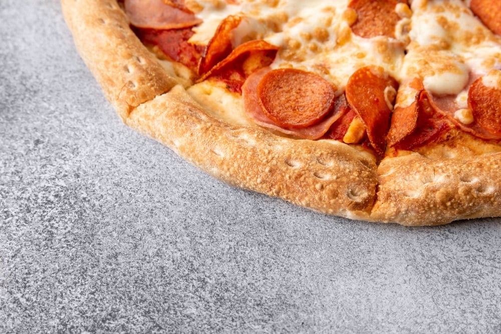 A pepperoni pizza on a grey background. 