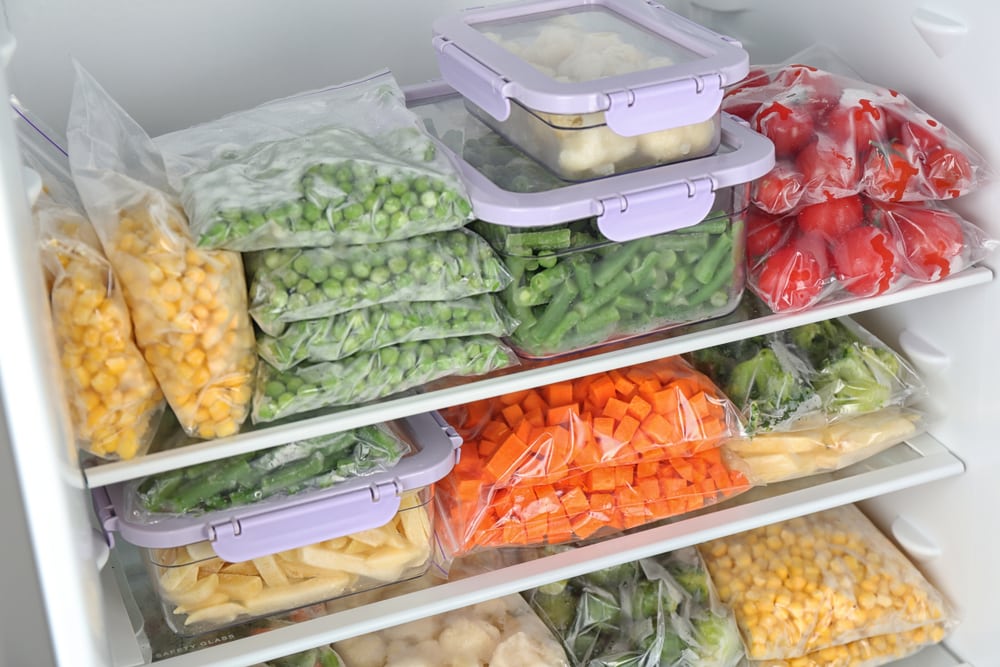 Freezer with pre-prepaired vegetables in plastic bags and containers.