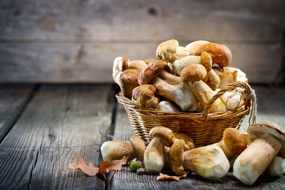 Basket of mushrooms on a wooden table.