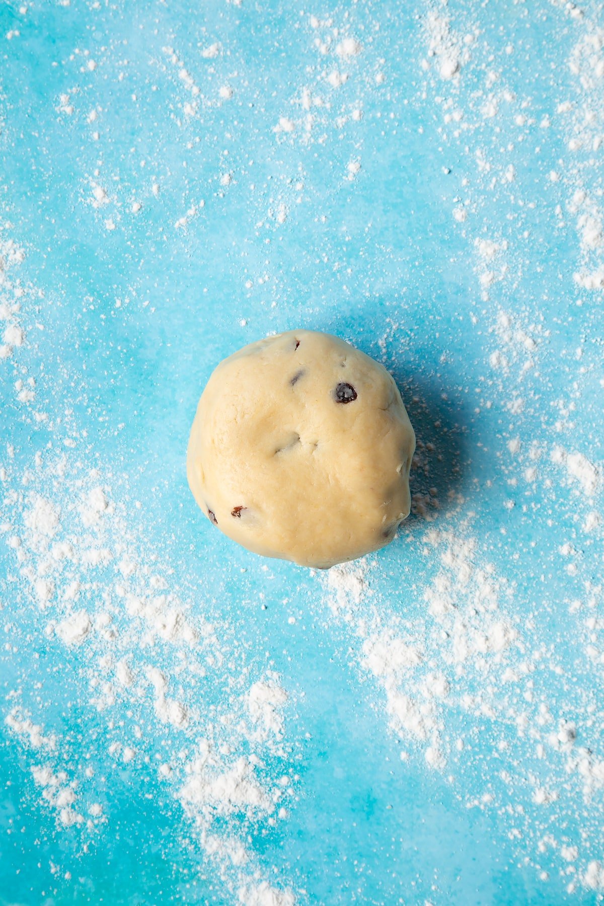 A Welsh cakes dough made from flour, butter, egg, sugar and sultanas on a floured surface.