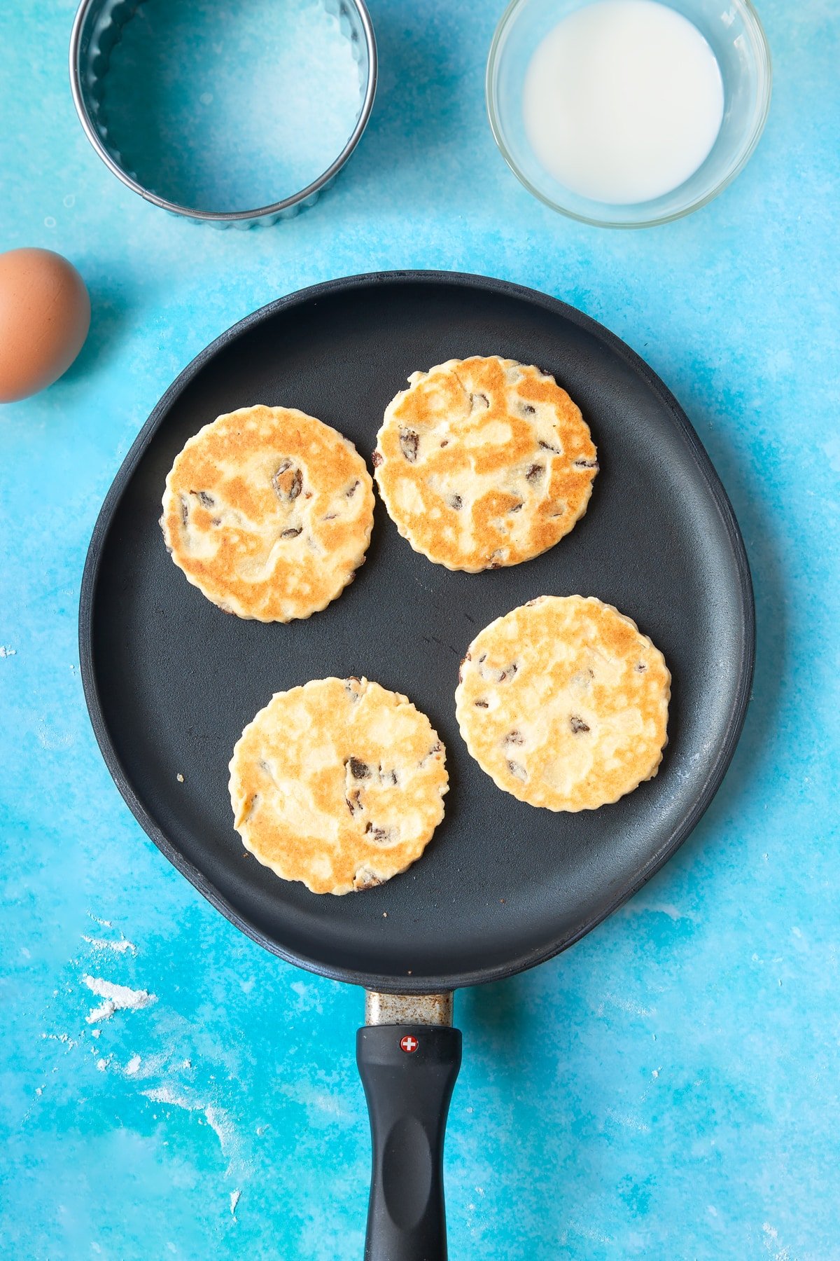 Cooked Welsh cake dough rounds in a hot, flat pan.