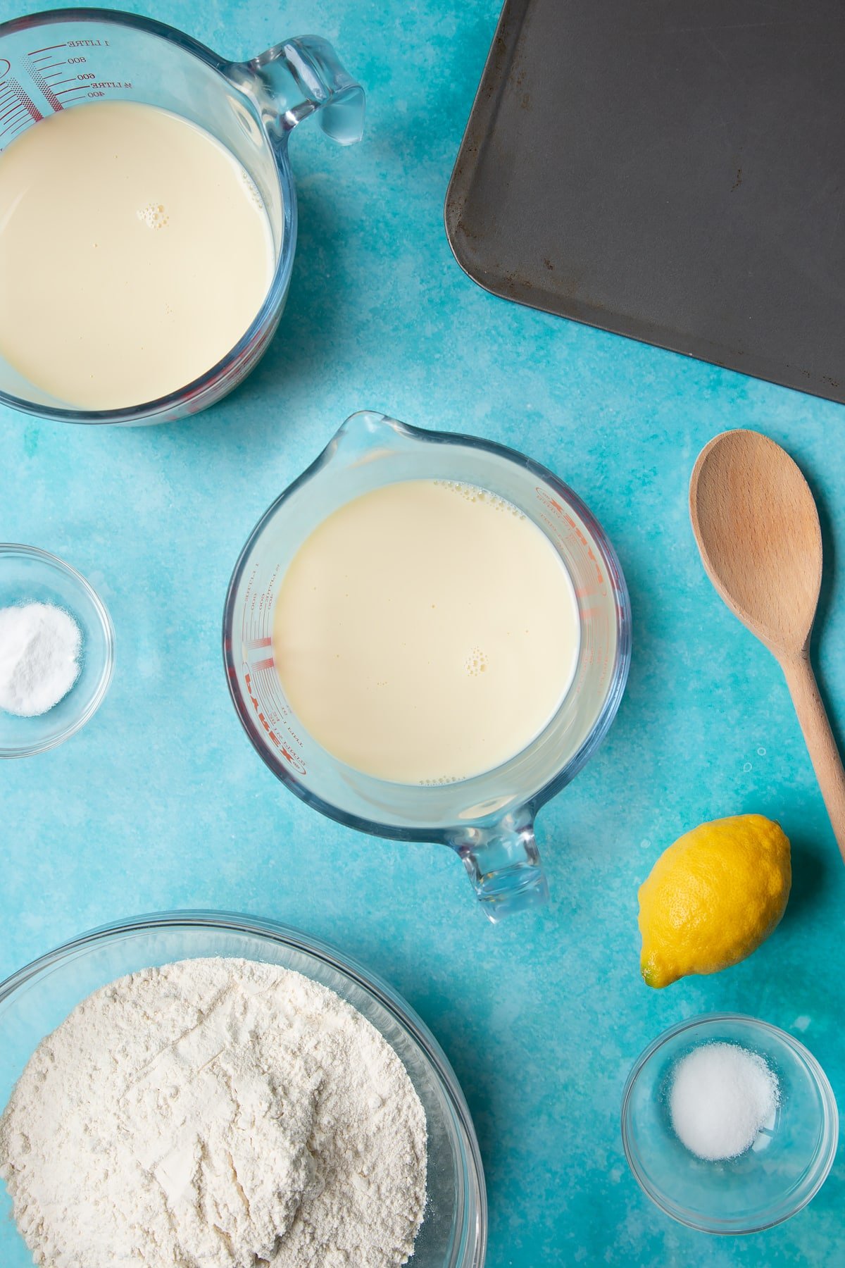 A jug containing plant milk. Ingredients to make vegan soda bread surround the jug.