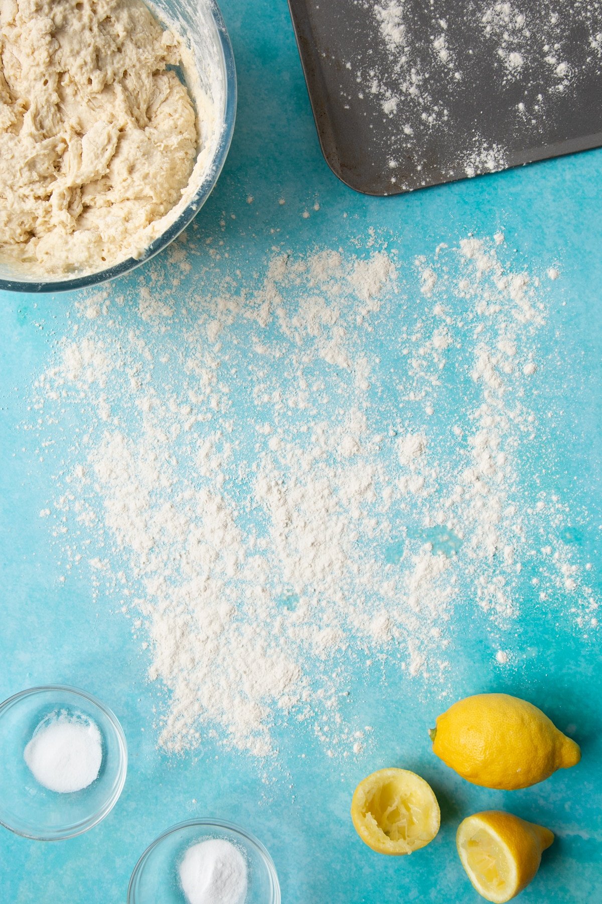 A floured surface surrounded by ingredients to make vegan soda bread.