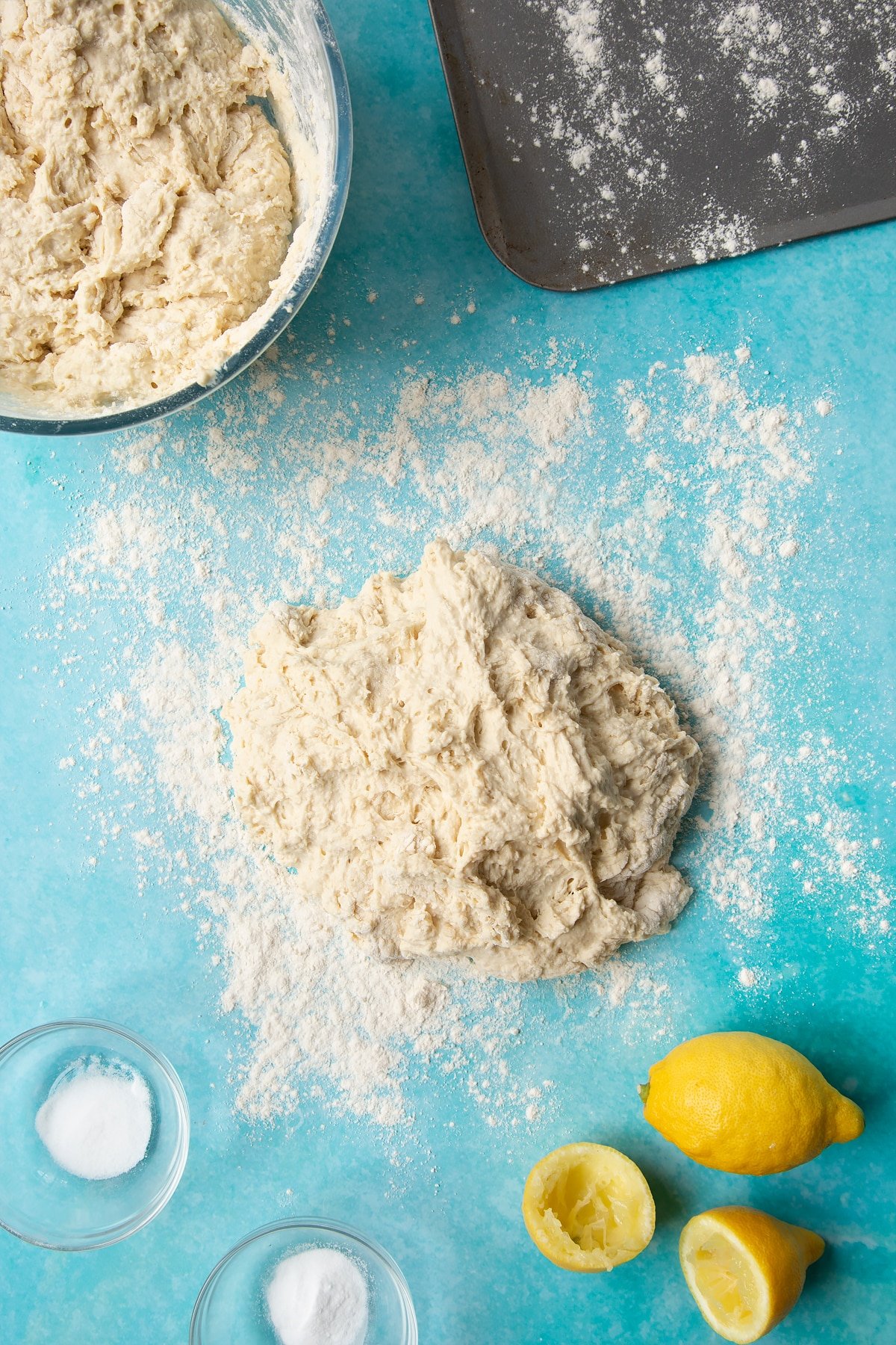 A wet dough on a floured surface surrounded by ingredients to make vegan soda bread.