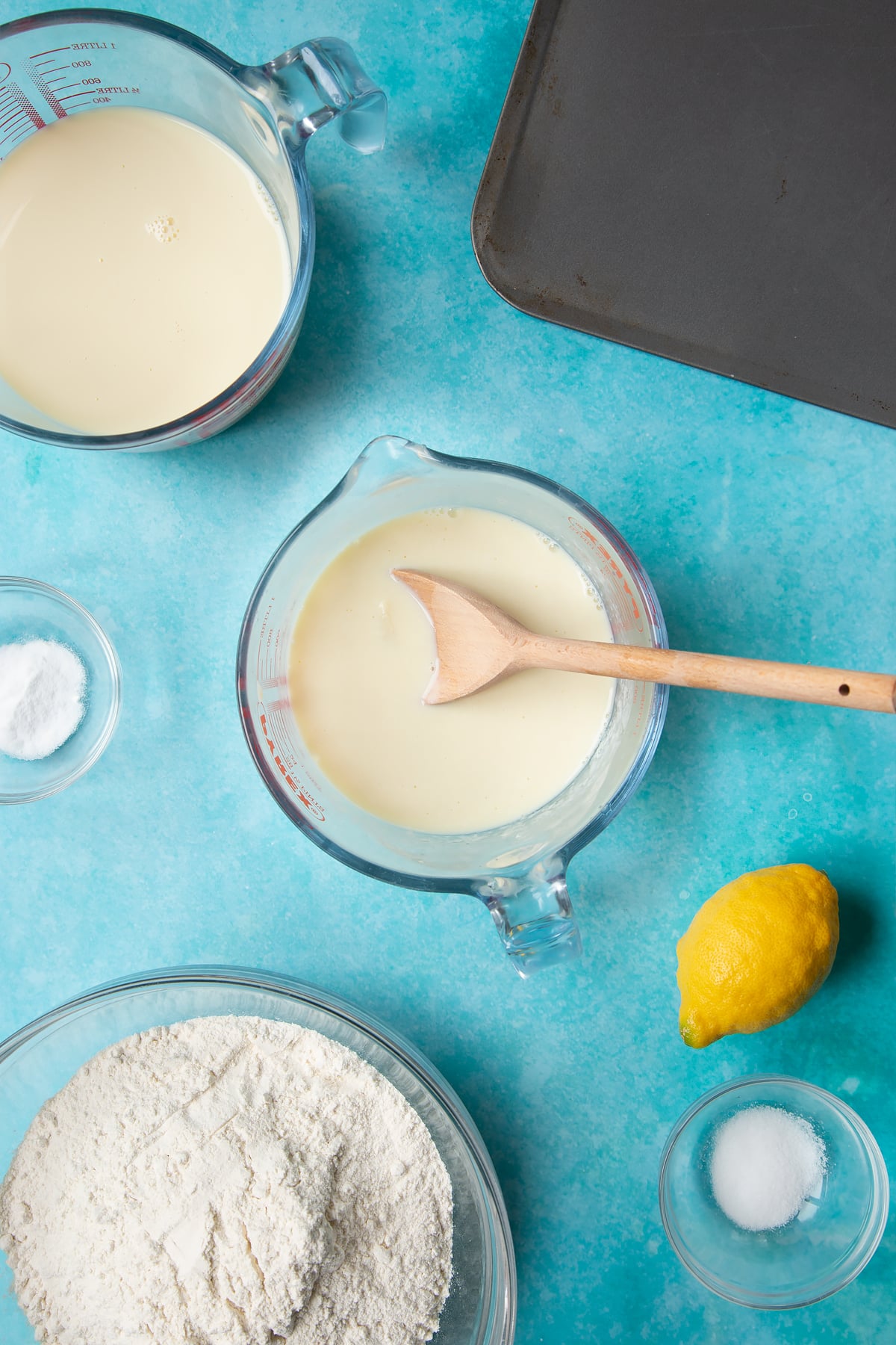 A jug containing plant milk and lemon juice. Ingredients to make vegan soda bread surround the jug.