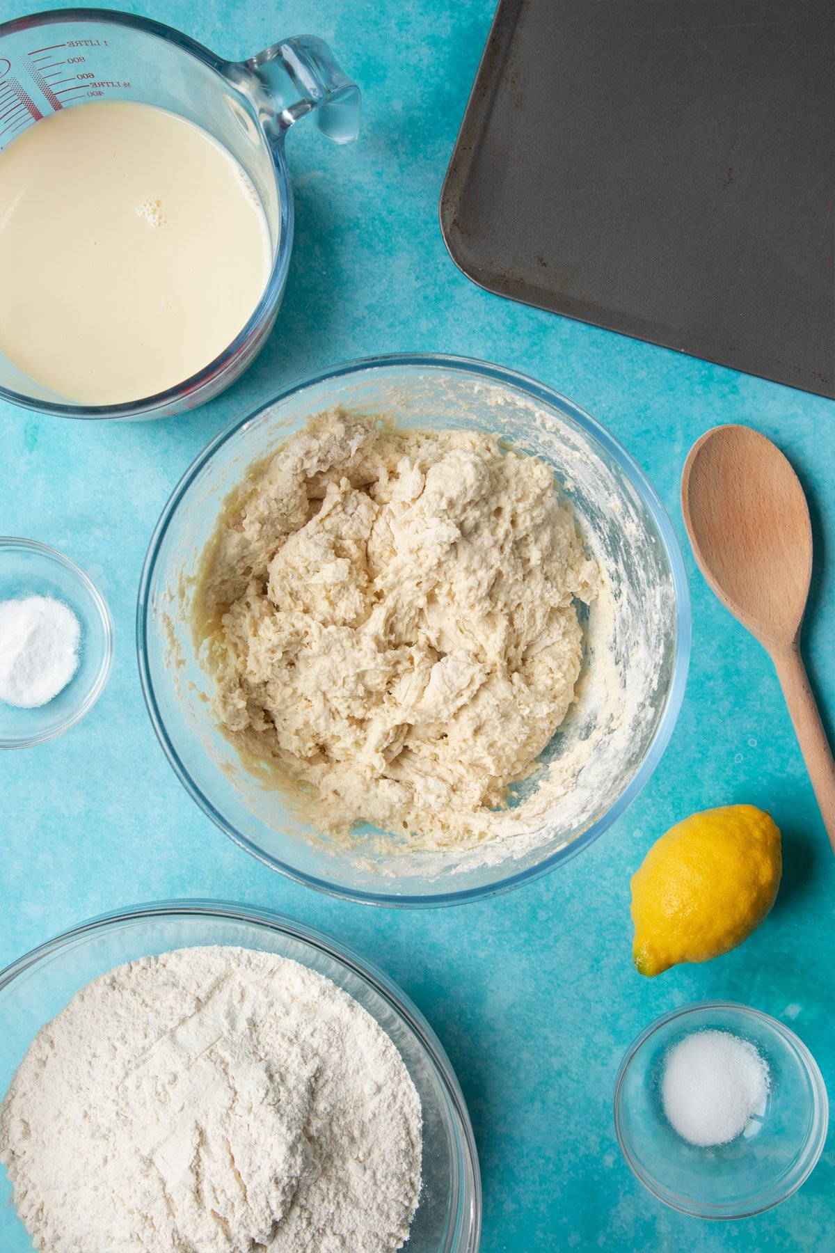 A bowl containing vegan soda bread dough. Ingredients to make vegan soda bread surround the bowl.