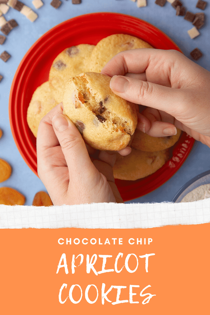 Apricot chocolate chip cookies stacked on a small orange plate. Hands break a cookie in half. Caption reads: apricot chocolate chips cookies