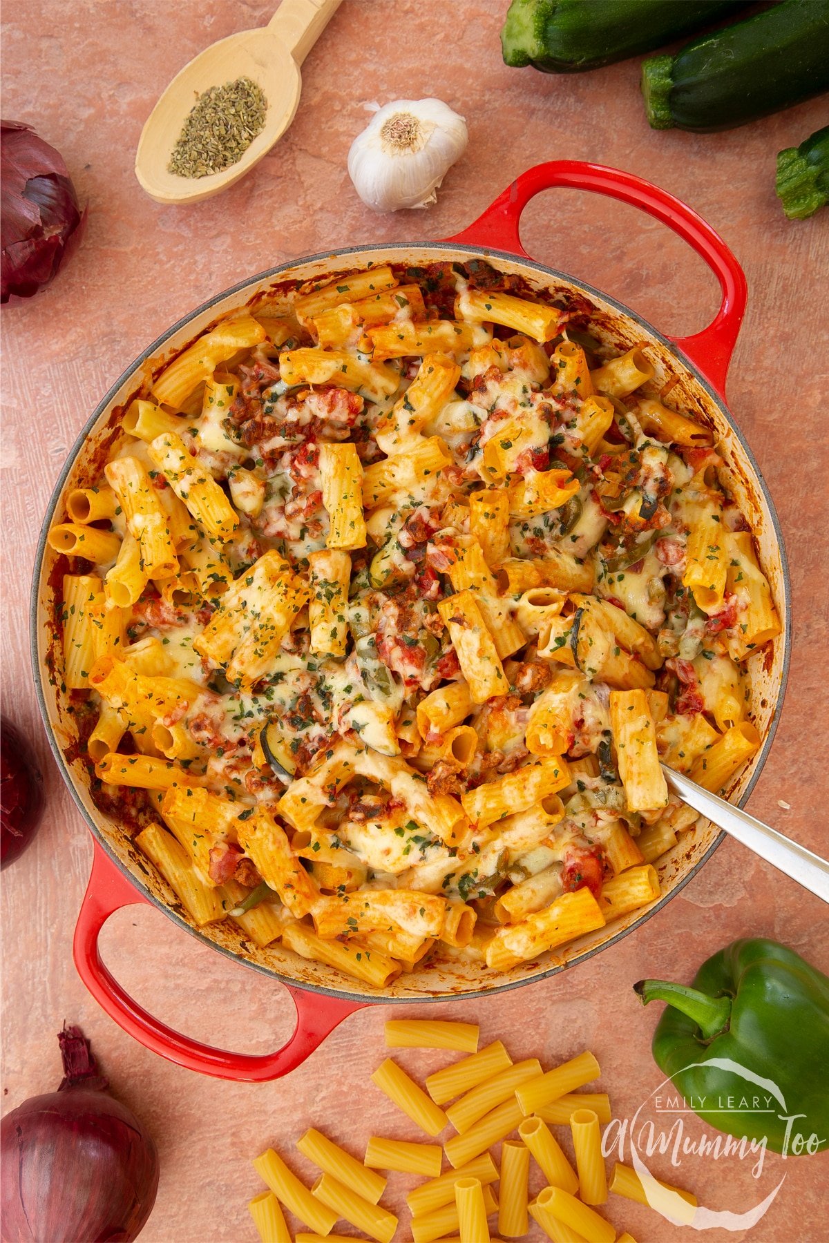 A casserole dish containing freshly baked bolognese al forno. A large serving spoon rests in the dish.