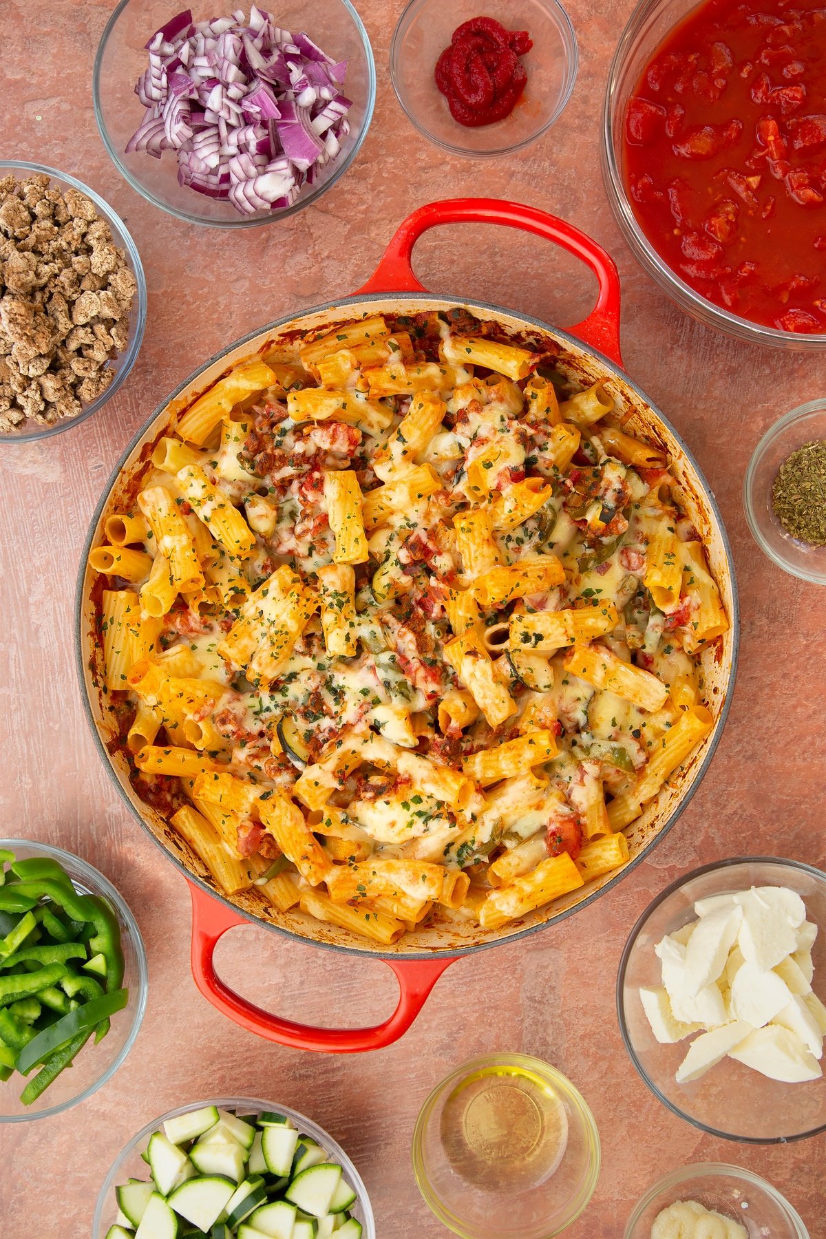 A casserole dish containing freshly baked bolognese al forno. Ingredients surround the dish.