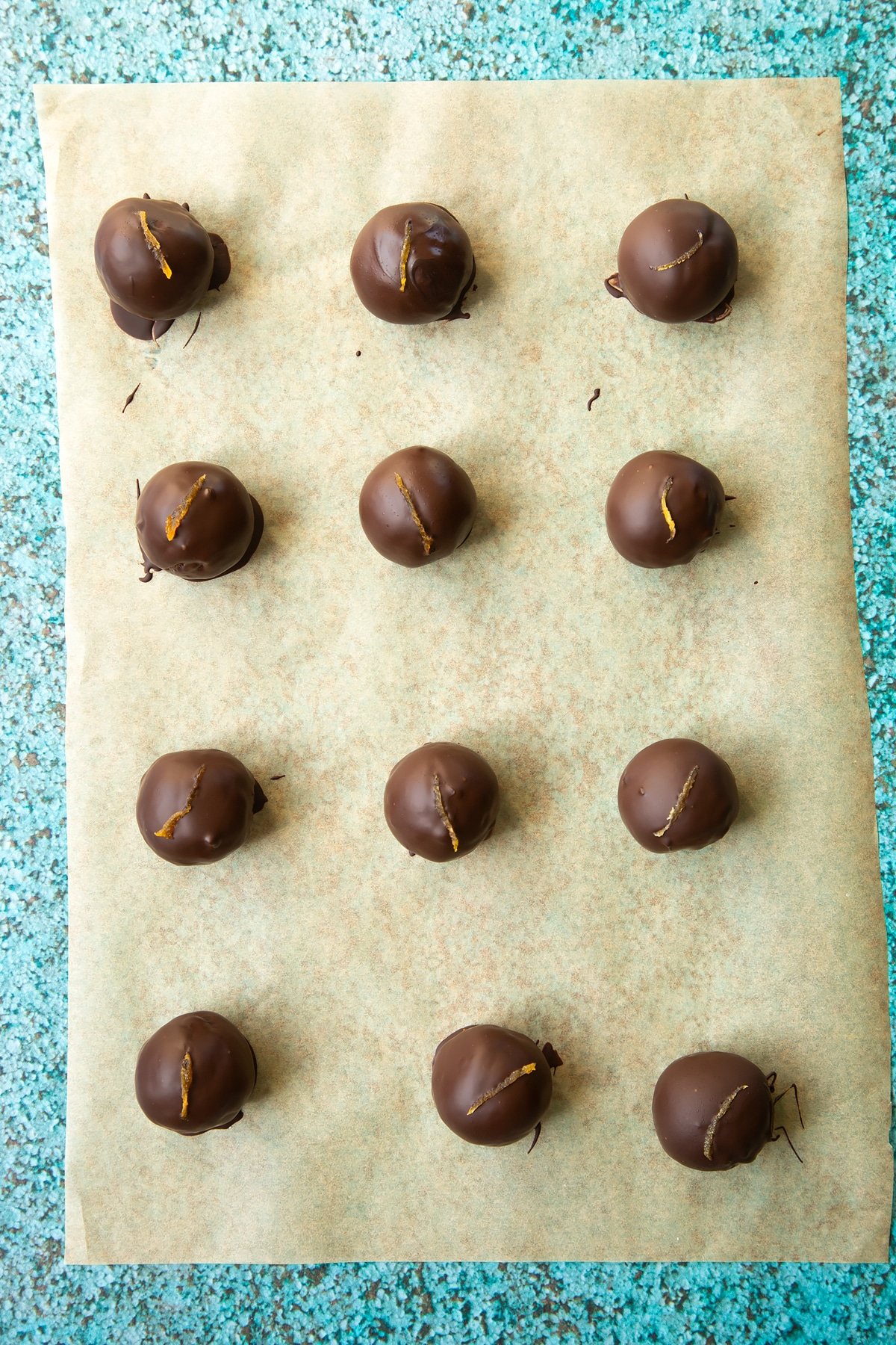 12 chocolate apricot balls on a piece of baking paper.