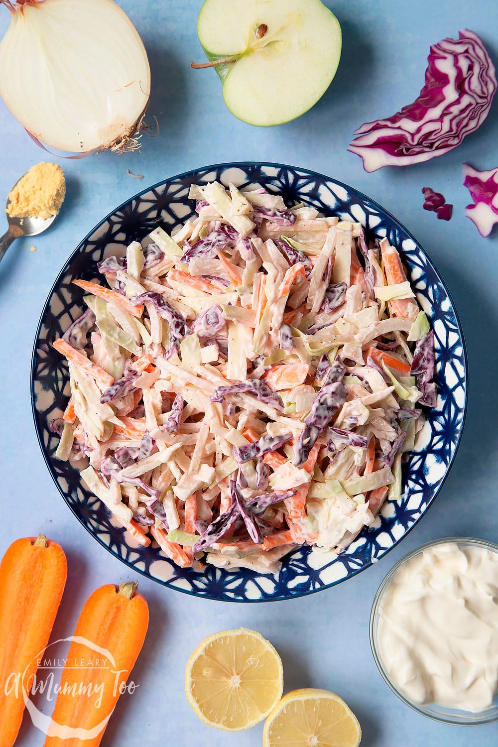 Creamy coleslaw without mayo served in a bowl. The bowl is surrounded by vegetables and creme fraiche.