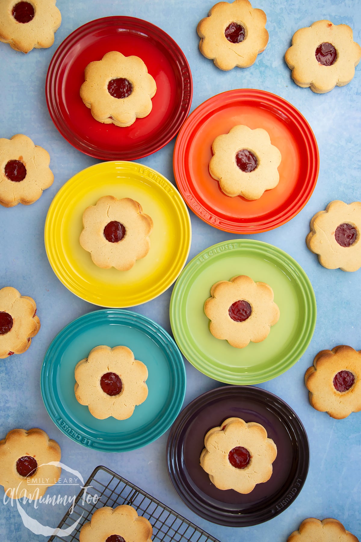 Giant jammie dodgers arranged on a variety of coloured small plates.