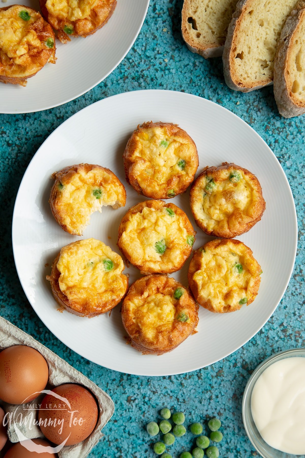 Mini vegetable frittatas arranged on a white plate. A hand reaches in to take a frittata.