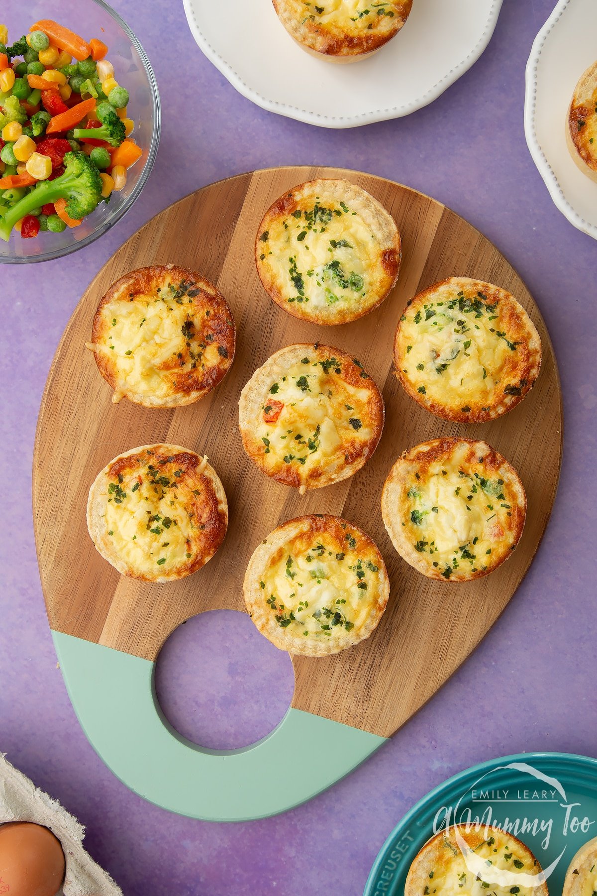 Mini vegetable quiches arranged on a wooden board.