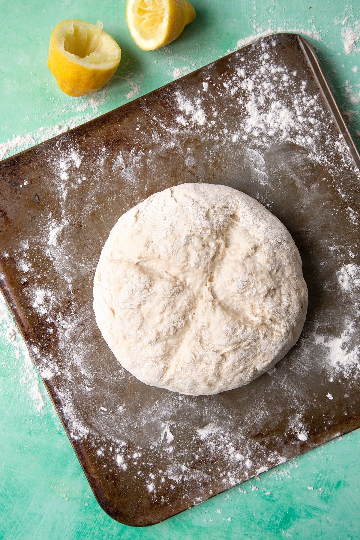 Dough to make a soda bread recipe without buttermilk placed on a floured baking sheet. A cross has been cut into the top.