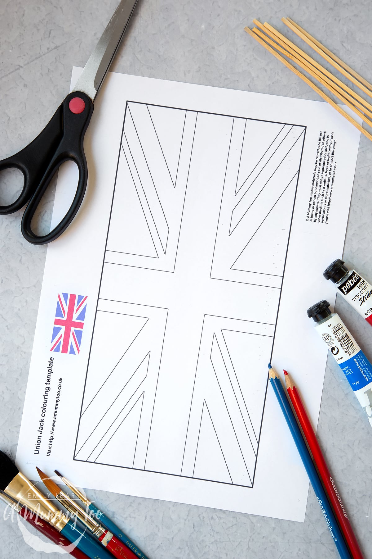 union jack flag printed onto A4 paper with scissors, glue and wooden sticks around the edges.