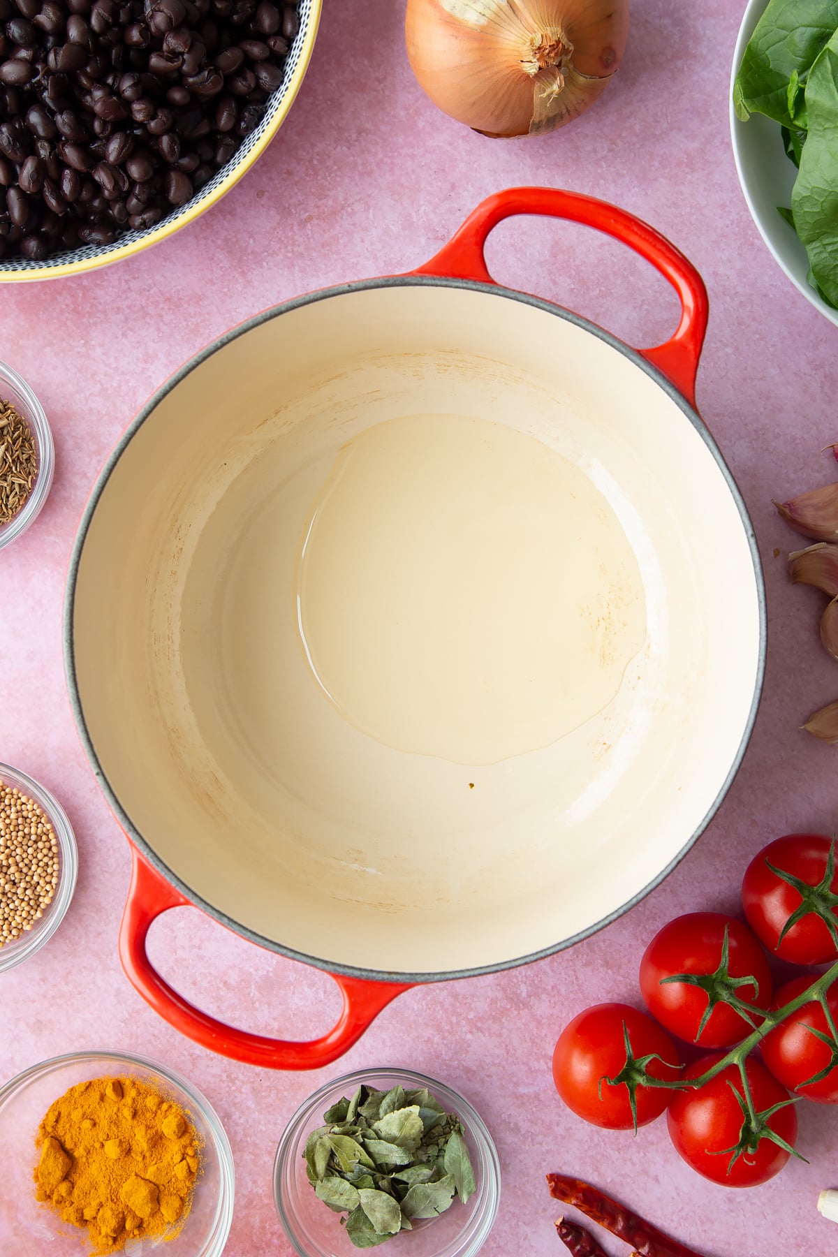 A saucepan containing oil. Ingredients to make black bean curry surround the pan.