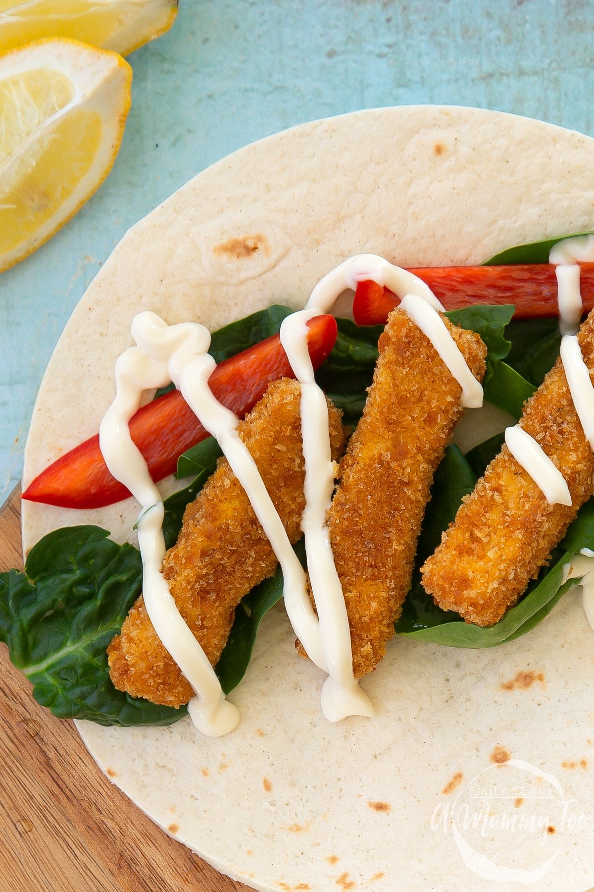 Close up of tofu fingers on a flour tortilla with salad and mayo. 
