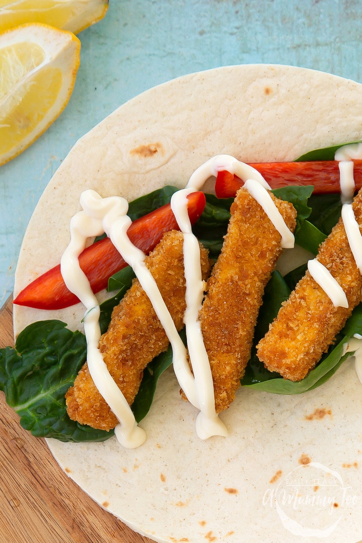 Close up of tofu fish sticks on a flour tortilla with salad and mayo.