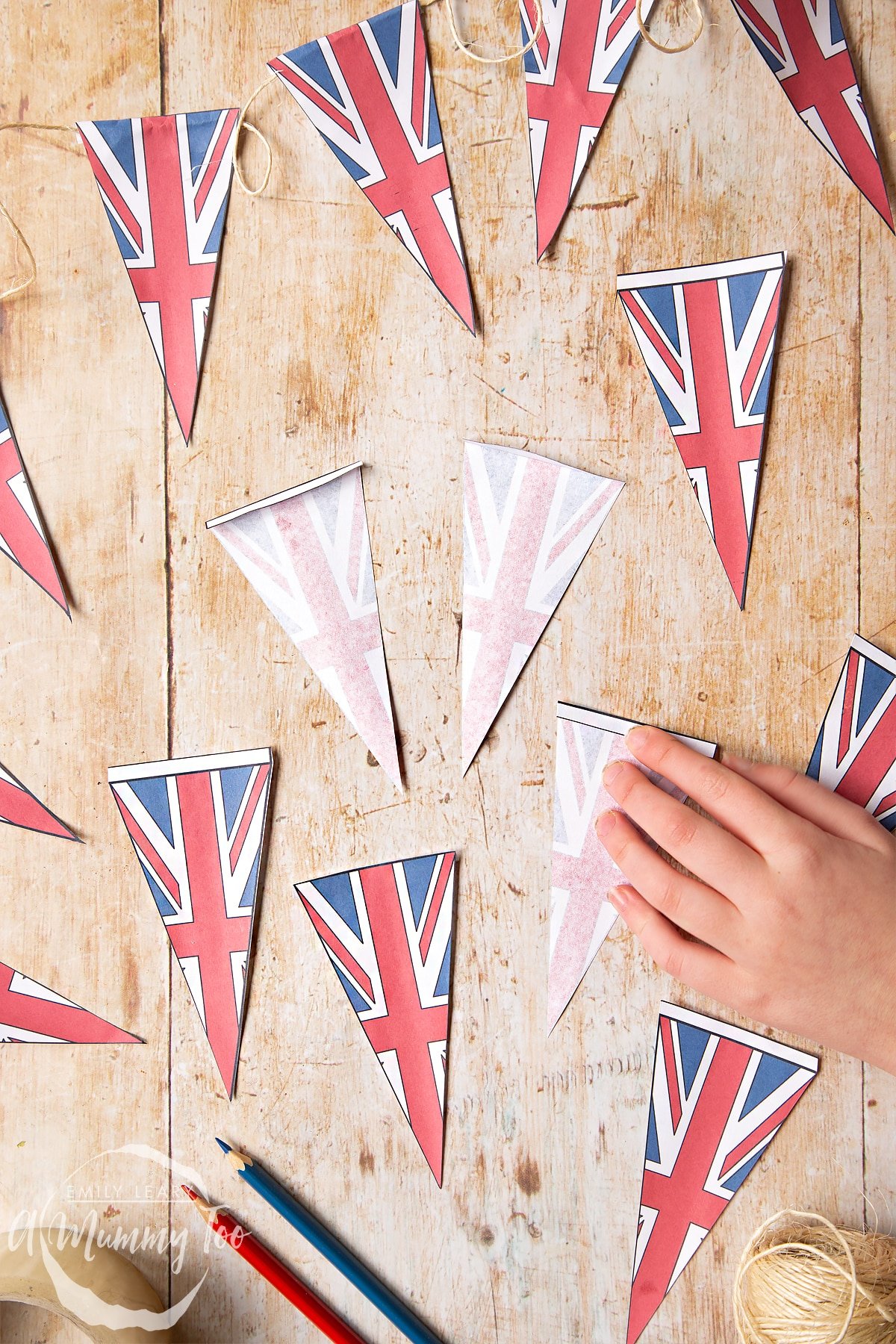 printed coloured sheet of union jack bunting being coloured in cut out and shown as individual pieces with teh folded tab towards the back